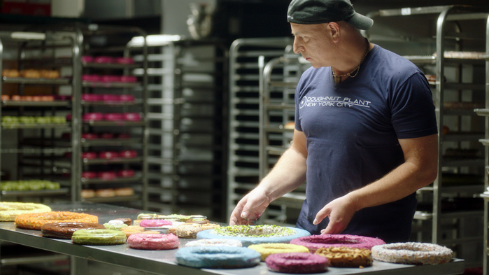 Mark Israel, founder of Doughnut Plant, is shown in his workspace with different kind of doughnuts.