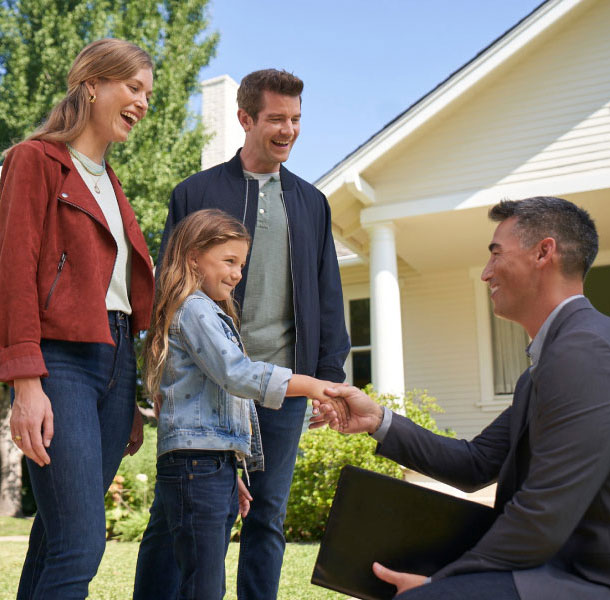  family standing outside of house shaking hands with man in suit