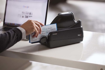 Cropped view of person inserting a check in to a MICR reader.
