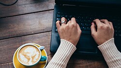 You're making more money. Here's how to save woman on a sofa with laptop looking at receipts