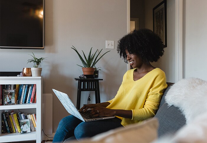 Savings Diaries: Tonya Rapley young african woman sitting on sofa with laptop