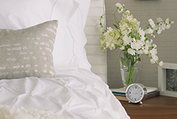 Create a calming bedroom bed with flower vase on night stand