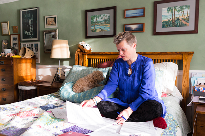 Savings Diaries: Kate Chapman middle age woman on bed doing paper work