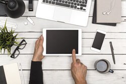 For cost-effective marketing, tap into LinkedIn person hands on tablet with laptop, mobile phone on desk