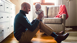 The costs of parenting: Stay at home or return to work? dad playing with infant kid