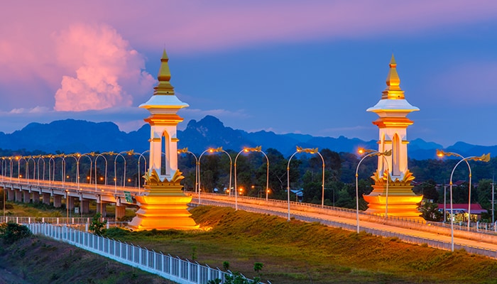 Travel is Changing- Laos evening view of wide boulevard with golden stupa on each side