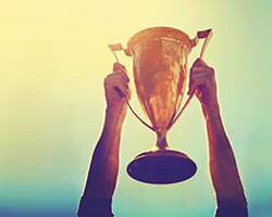 Achieve Real Victory person holding a trophy