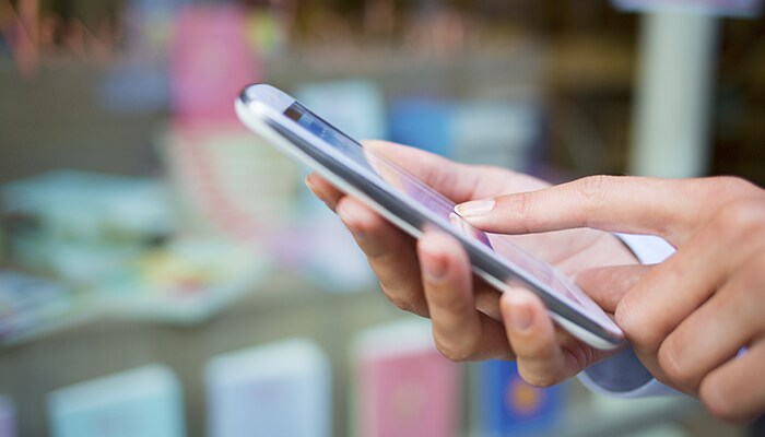 How to save money on college textbooks person's hands holding smartphone