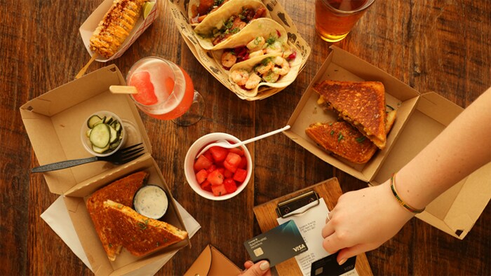 Charlotte Travel Guide soft tacos, corn, sandwiches and drinks on table next to hands holding Chase Sapphire Reserve card