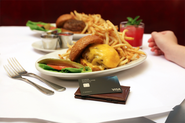 NYC Travel Guide burger, fries in a plate on table along with Chase Sapphire card on a wallet