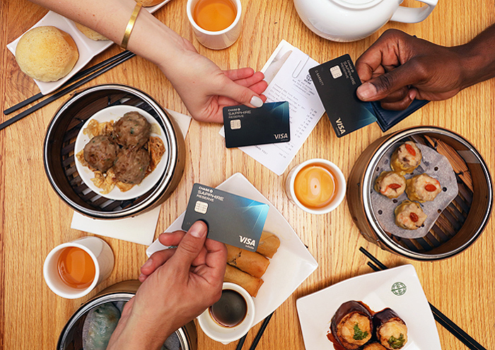NYC Travel Guide food on a table with hands holding their Chase Sapphire card