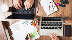 7 keys to avoiding a cash flow crisis top view of desk with couple laptops with hands on keyboard