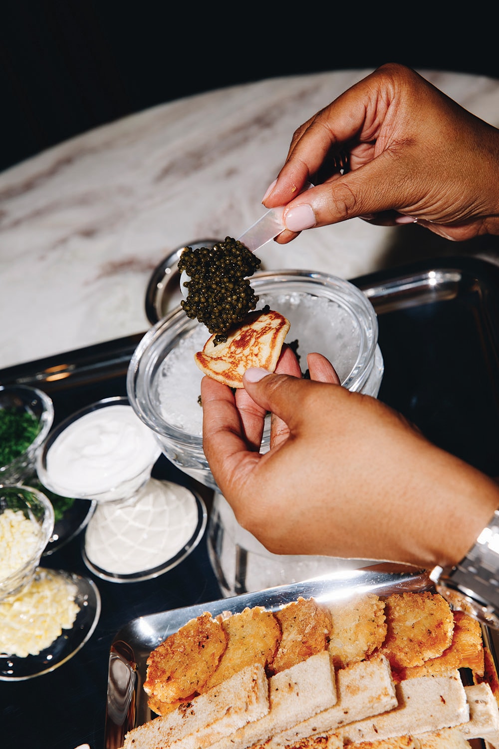 A person pours caviar onto bread.