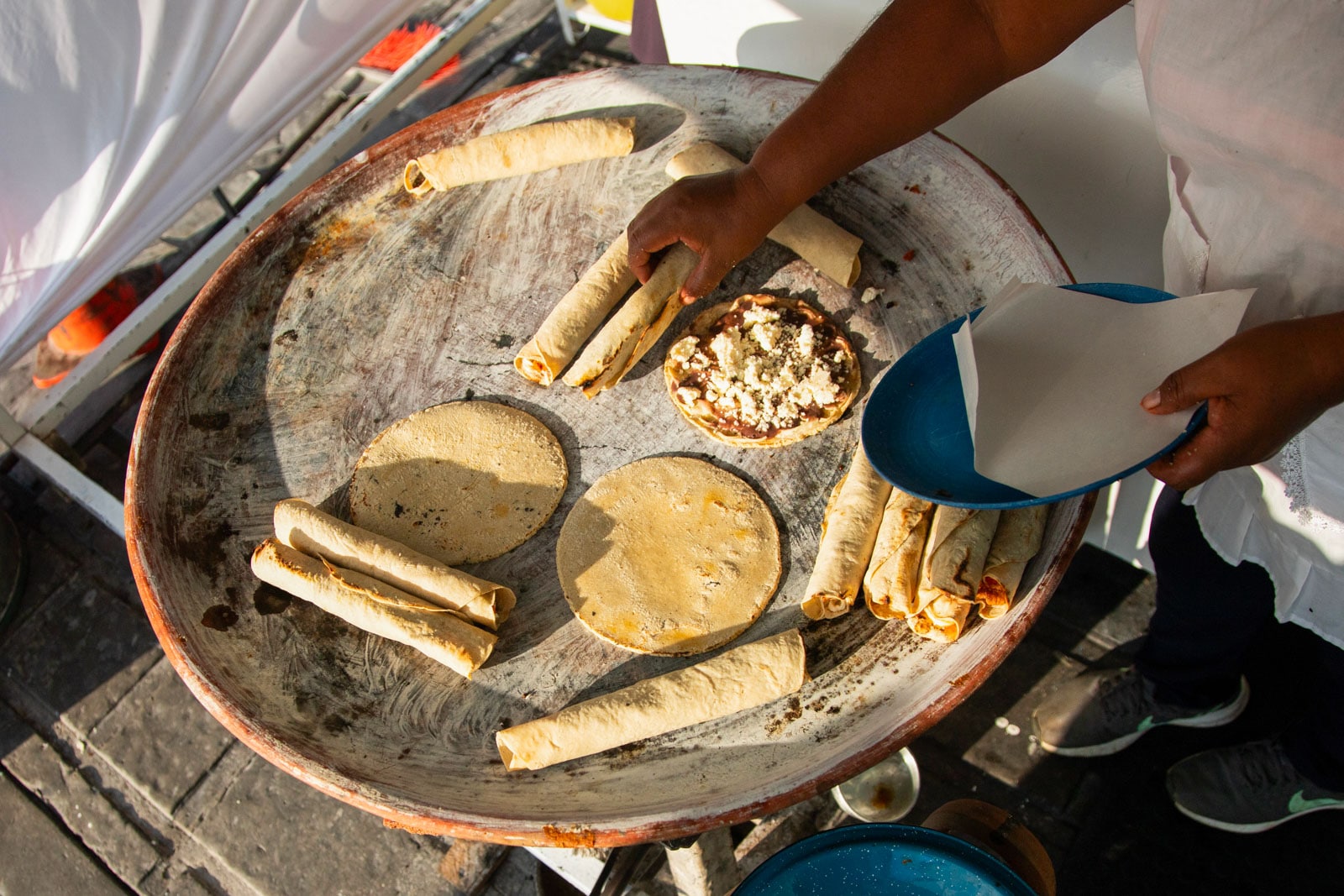 A woman cooking tortillas, flautillas and Mexican memelas on a comal on a street in Oaxaca.