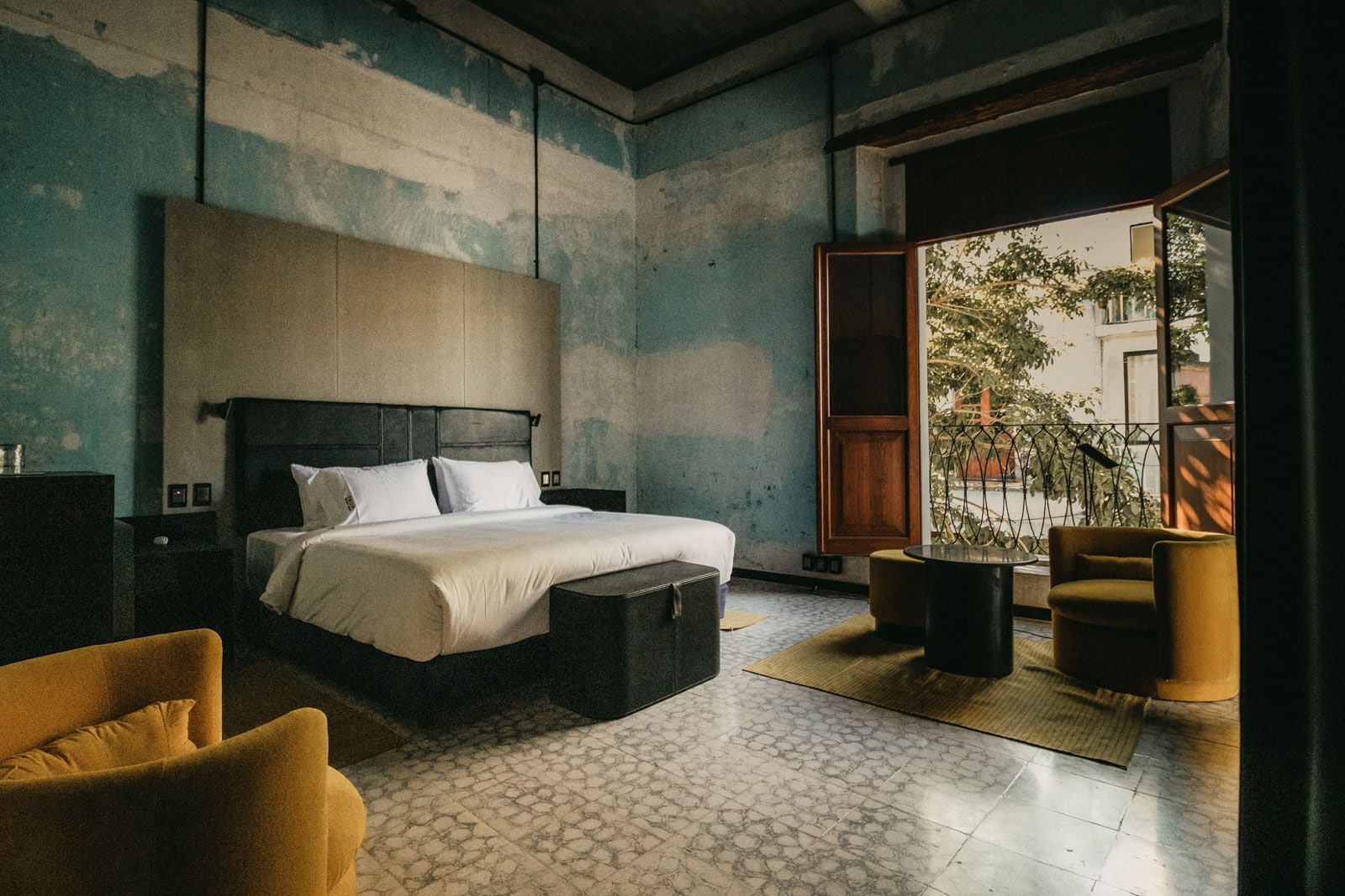 Bedroom with stone floor, seating area and balcony.