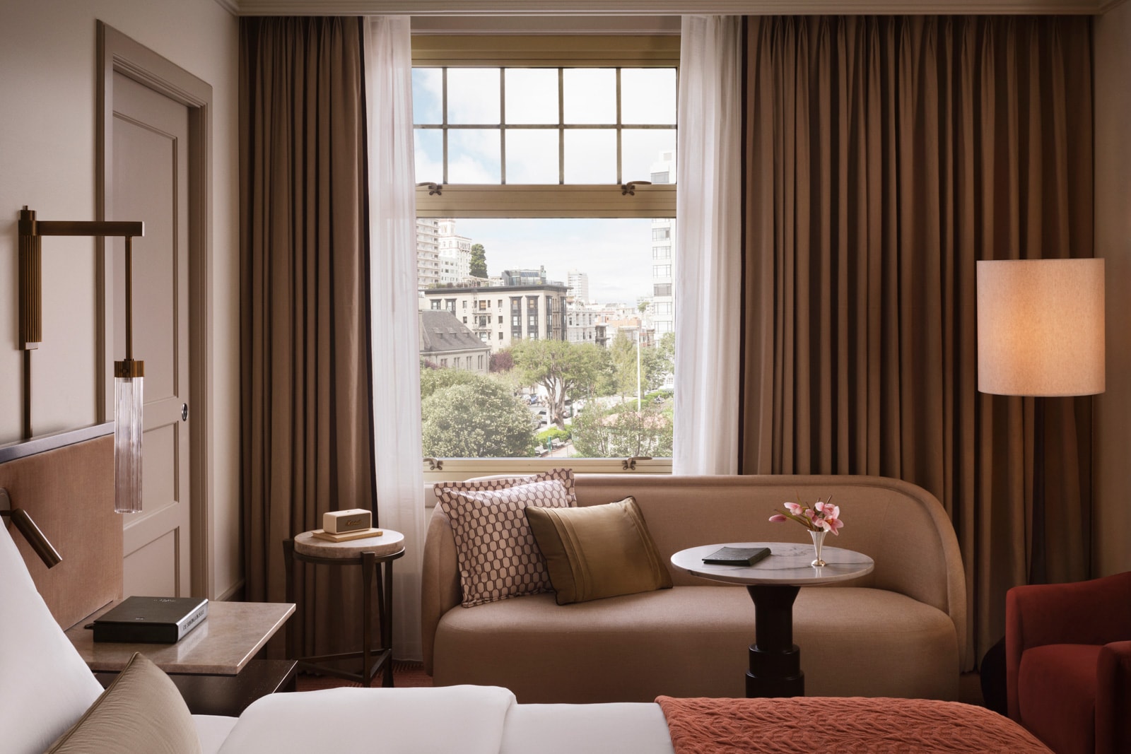 A hotel bedroom features a settee, a king bed, and blackout curtains.