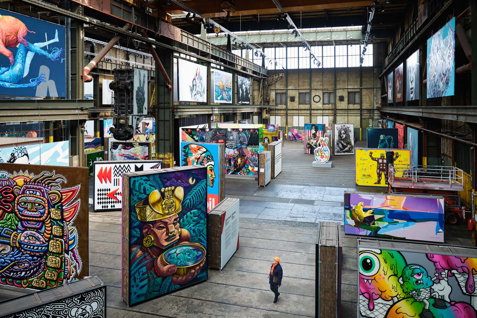 Colorful indoor street art exhibition in a large industrial hall.