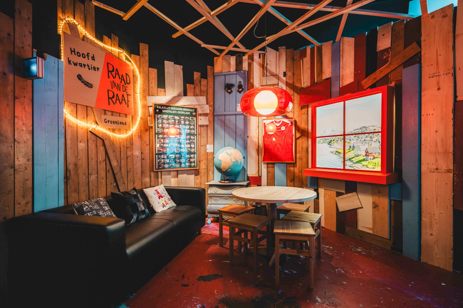 Cozy room with a sofa, round table, globe, and playful wall decorations.