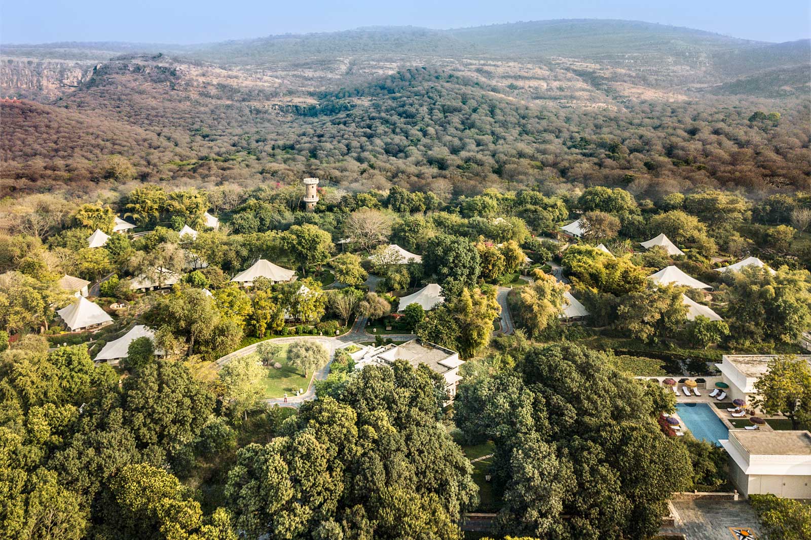 A resort property sits within a forest surrounded by hilly terrain.