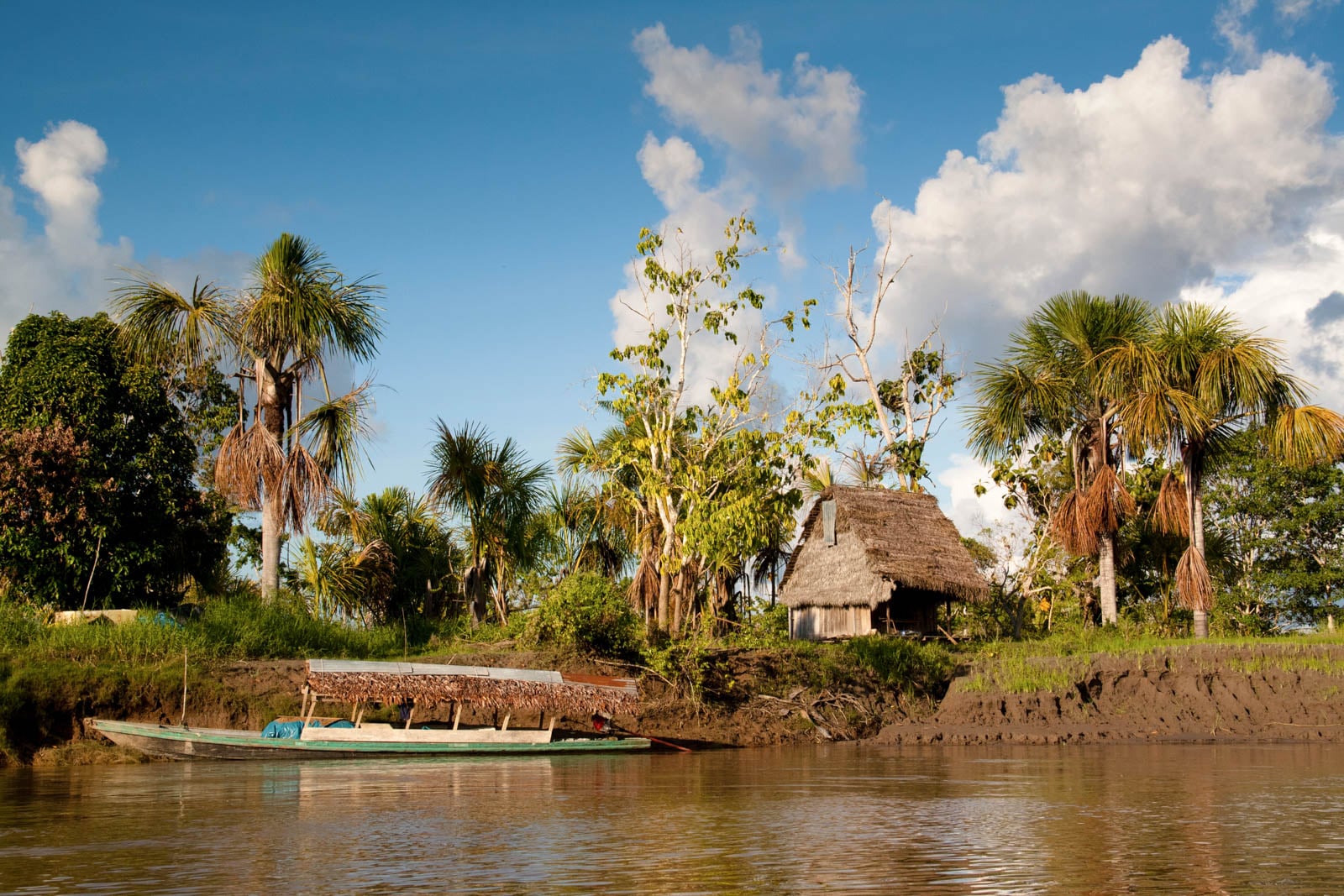 A building with thatch roof stands next to a river.
