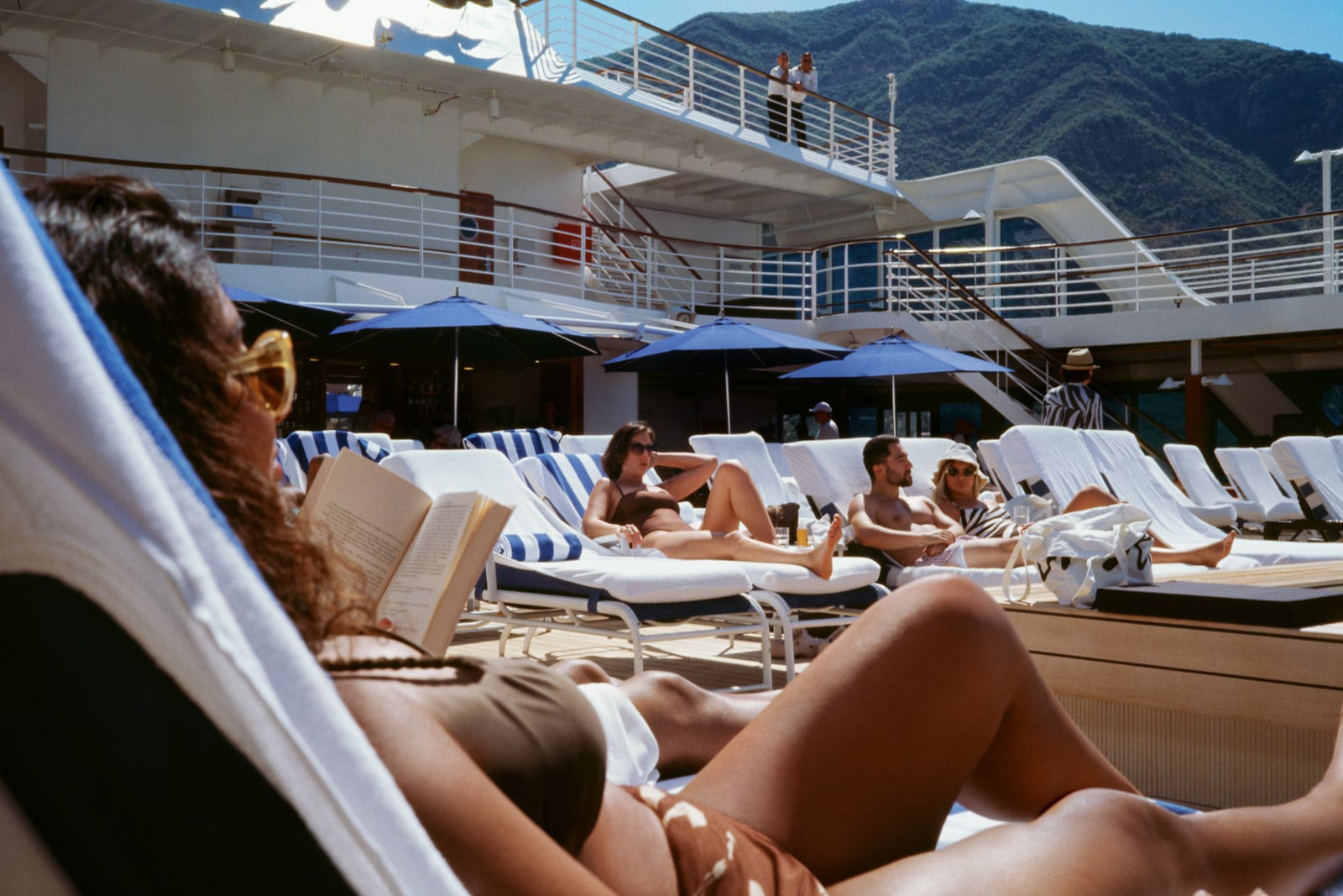 Guests lie on lounge chairs on the sundeck of a cruise ship.
