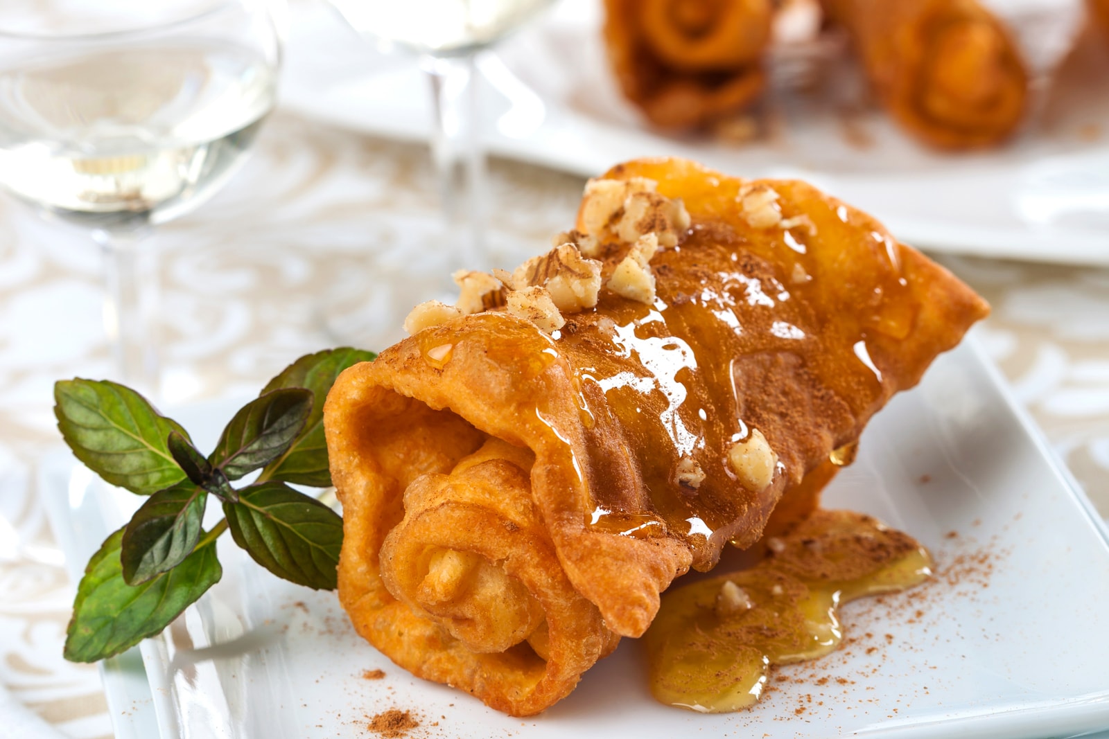 Greek diples, or thin sheets of dough folded while fried and drizzled with honey, displayed on a plate.