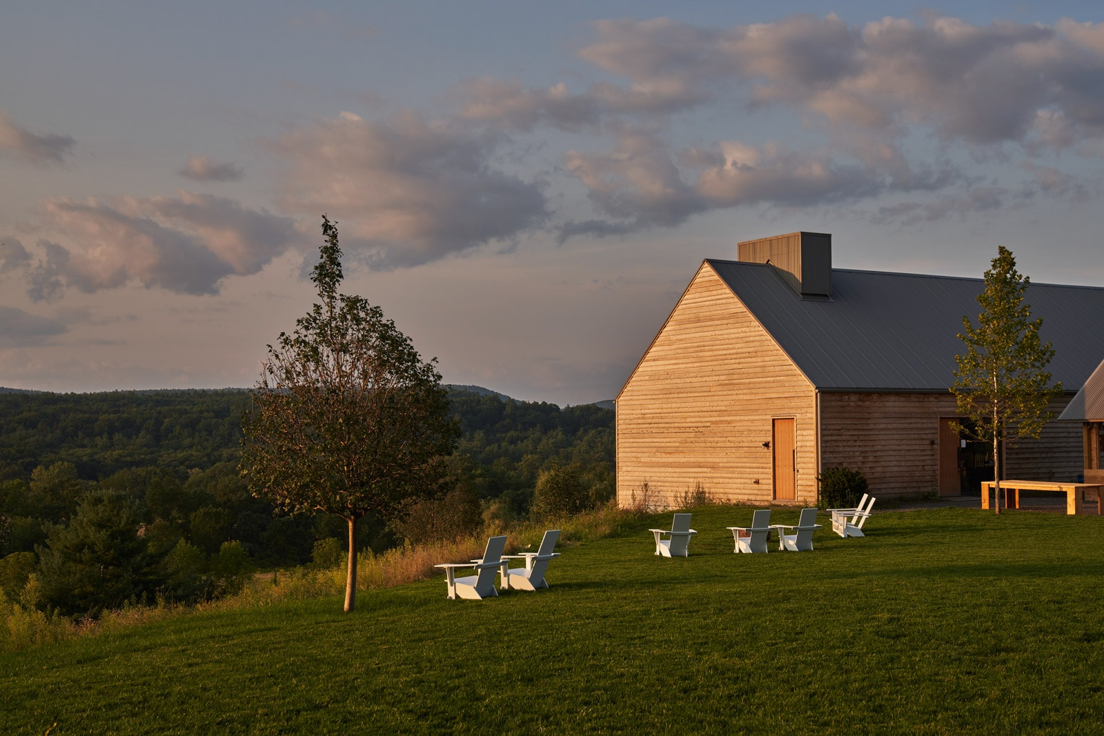 View of farmhouse with low forested mountains in the background.