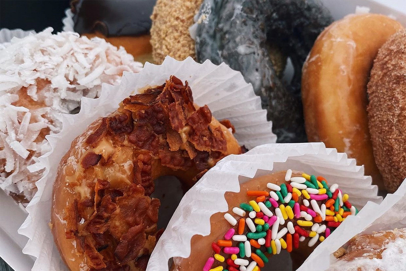 Several donuts sit lined up in wax paper.