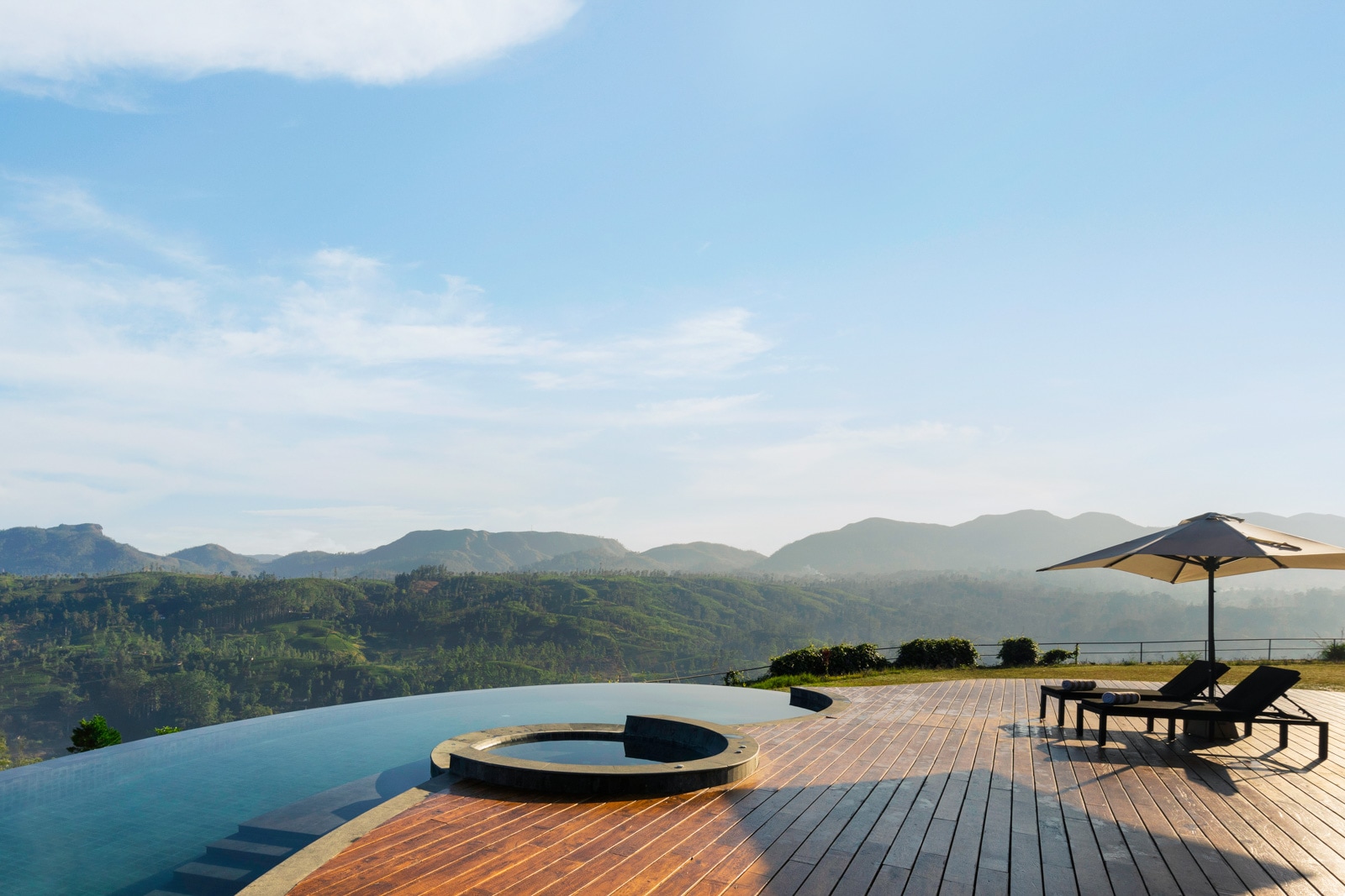 A terrace with a pool overlooks mountains in the distance.
