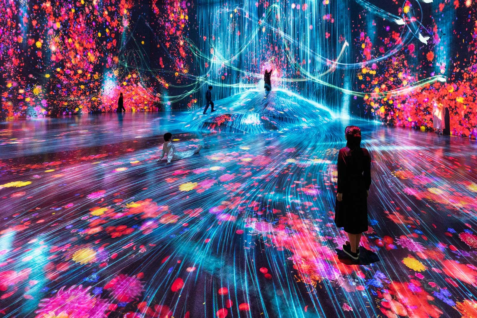 Immersive digital art installation with vibrant lights and floral projections on walls and floor.