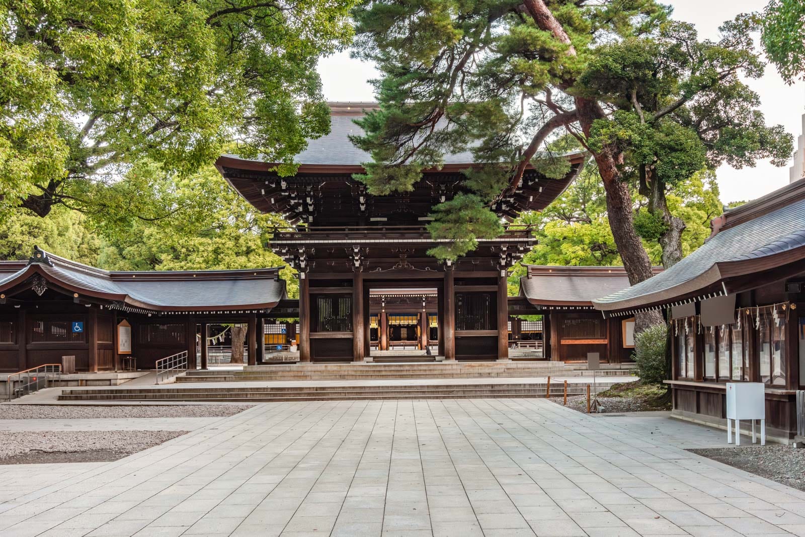 Traditional Japanese shrine with wooden buildings and lush green trees.