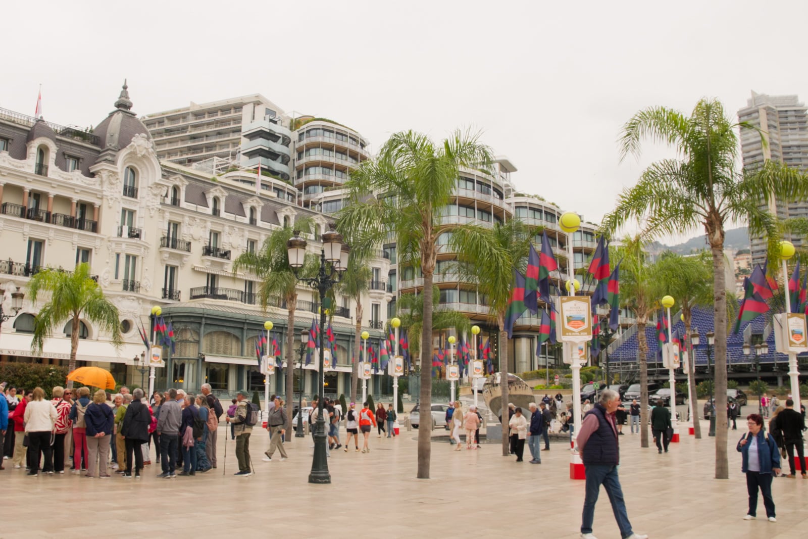 Visitors walk through a plaza dotted with palm trees.