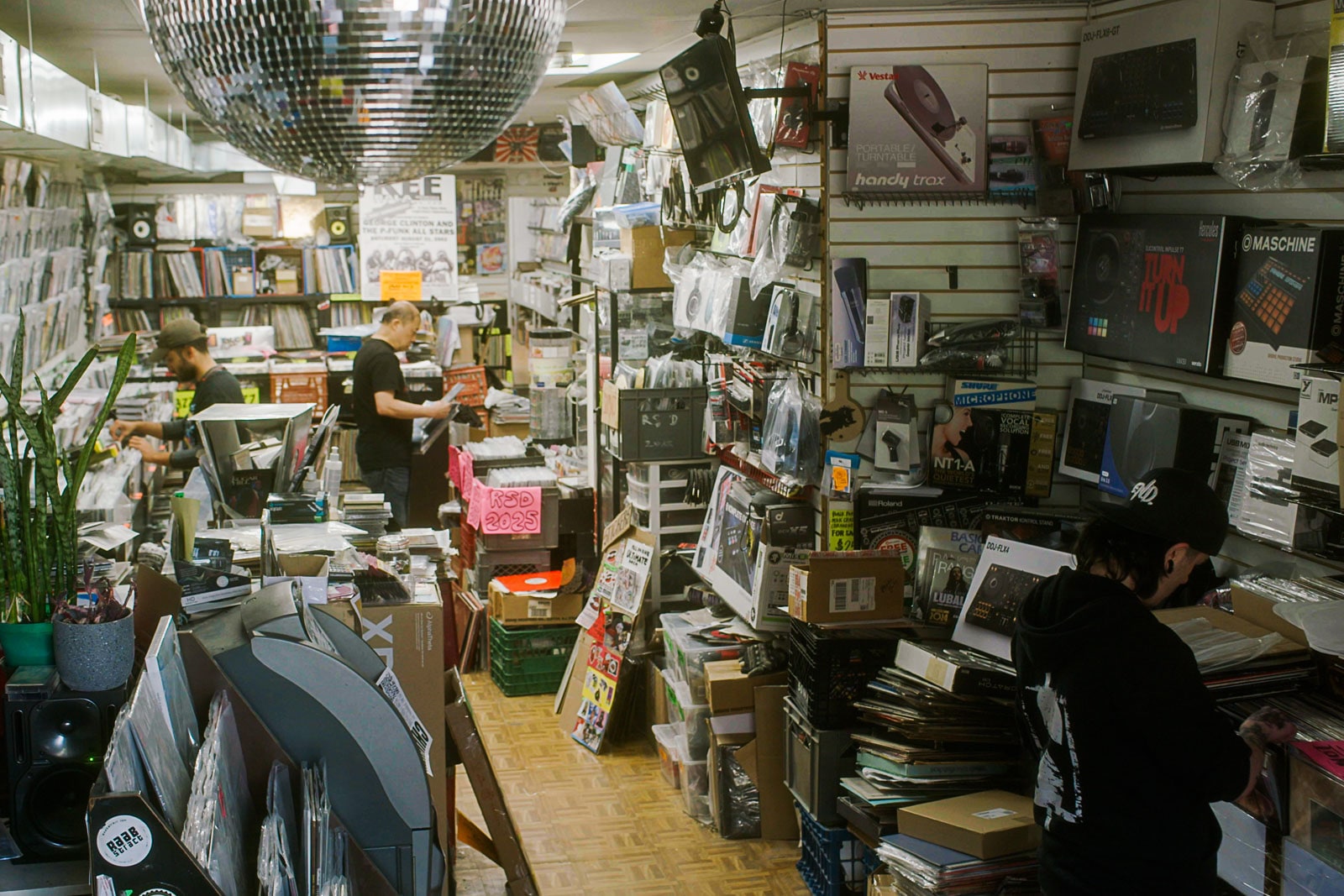 Two men stand searching through racks of records at a store.