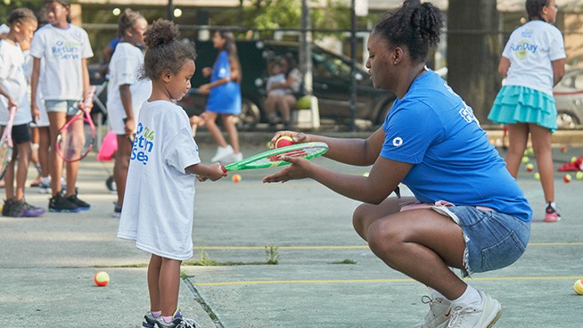 Instructor teaching tennis basics to a young player
