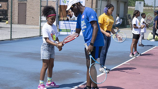 Instructor teaching tennis basics to a young player